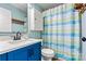 Cozy bathroom features blue vanity, tub with colorful shower curtain, and classic fixtures at 4920 Longfield St, Claremont, NC 28610