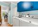 Laundry room with blue upper cabinets and modern, white, side-by-side washer and dryer at 4920 Longfield St, Claremont, NC 28610