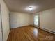 This bedroom has hardwood floors, white walls, a light, a window, and a closet at 511 Evelyn Ave, Kannapolis, NC 28083