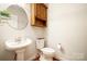 Half bathroom featuring pedestal sink, toilet, medicine cabinet, and hardwood floors at 803 Freeman Rd, Concord, NC 28025