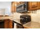 Close up of traditional kitchen with oak cabinets and black stove and microwave at 803 Freeman Rd, Concord, NC 28025