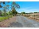 Long gravel driveway with a rustic wooden fence, leading to a secluded property at 10016 Morgan Mill Rd, Monroe, NC 28110