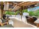 Outdoor patio with a covered area, bar seating, and multiple wood chairs. View of the wooded yard at 10016 Morgan Mill Rd, Monroe, NC 28110