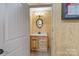 Rustic powder room with wood paneling, vanity with light countertop, decorative mirror, and wall sconces at 10016 Morgan Mill Rd, Monroe, NC 28110