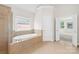 Well-lit bathroom with a soaking tub and a view into the carpeted bedroom at 10024 Hazelview Dr, Charlotte, NC 28277