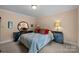 Well-lit bedroom showcasing patterned bedding, stylish dressers, and a decorative circular mirror at 10317 Clubhouse View Ln, Mint Hill, NC 28227