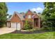 Charming brick home featuring a well-manicured lawn, mature trees, and a three car attached garage at 10317 Clubhouse View Ln, Mint Hill, NC 28227