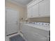 Bright laundry room with white cabinets and appliances next to a door and large blue rug at 10317 Clubhouse View Ln, Mint Hill, NC 28227