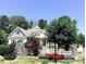 Picturesque home exterior with stone accents, a white picket fence, and lush landscaping at 104 Bunker Way # 1001, Mooresville, NC 28117