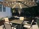 Outdoor patio area with a fire pit table, four chairs, and patio umbrella with string lights at 104 Bunker Way # 1001, Mooresville, NC 28117