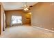 Bright living room with neutral carpet, ceiling fan, and large windows with decorative curtains at 10927 Chrudan Dr, Charlotte, NC 28262