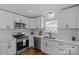 Updated kitchen boasts stainless appliances, white cabinets and countertops, with modern fixtures at 1814 Brookdale Ave, Charlotte, NC 28210