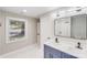 Updated bathroom featuring double sinks, square mirror, and a window providing natural light at 2000 Tyvola Rd, Charlotte, NC 28210