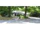 View of the house from the street, partially obscured by mature trees and landscaping at 2000 Tyvola Rd, Charlotte, NC 28210
