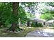Home's exterior featuring a green lawn and a curved driveway, surrounded by mature trees at 2000 Tyvola Rd, Charlotte, NC 28210
