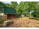Exterior of green barn with access to fenced grazing pasture with sheds in the distance at 2865 Water Plant Rd, Maiden, NC 28650