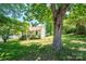 The front of the white house has big trees with green leaves and a lush green lawn at 3042 N Oxford St, Claremont, NC 28610