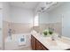 Well-lit bathroom featuring double sinks, a soaking tub, and a large mirror at 4135 Twenty Grand Dr, Indian Trail, NC 28079