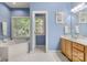Light blue bathroom featuring a soaking tub with blinds in front of the window and wood cabinets at 4389 Enchantment Cove Ln, Charlotte, NC 28216