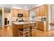 Well-lit kitchen features wood floors, wood cabinetry, a center island, and a range with stainless hood at 4389 Enchantment Cove Ln, Charlotte, NC 28216
