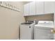Convenient laundry room features a modern washer and dryer with white cabinets for ample storage at 4389 Enchantment Cove Ln, Charlotte, NC 28216