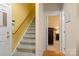Carpeted stairway with wooden handrail leads to the upper level, complemented by yellow walls at 4389 Enchantment Cove Ln, Charlotte, NC 28216