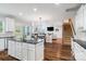 Open-concept kitchen with an island, white cabinets, hardwood flooring, and seamless dining area at 6430 Stirling Ln, Indian Land, SC 29707