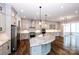 Open kitchen and dining area with stainless appliances, island, and hardwood floors at 720 Cavesson Way, Monroe, NC 28110