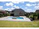 Backyard view of a refreshing swimming pool with a stone waterfall feature and a spacious patio area at 720 Cavesson Way, Monroe, NC 28110