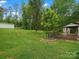 Expansive green backyard featuring a wooden deck with a gazebo and a greenhouse on a sunny day at 730 Cove Rd, Gastonia, NC 28052