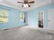 Carpeted bedroom with blue walls, tray ceilings, ceiling fan, and natural light from the windows at 730 Cove Rd, Gastonia, NC 28052