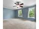 Spacious bedroom with two windows, a ceiling fan, carpet floors, and light blue painted walls at 730 Cove Rd, Gastonia, NC 28052
