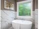 Elegant bathroom features a standalone tub with marble tile accents and a large window with natural light at 7703 Juniper Ln, Denver, NC 28037