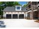 Three-car garage featuring elegant black doors, outdoor lanterns, and stone exterior at 7703 Juniper Ln, Denver, NC 28037