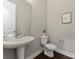 Elegant powder room featuring a pedestal sink, modern fixtures, neutral paint, and a decorative art piece at 859 Academy St, Charlotte, NC 28205