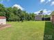 Expansive backyard featuring a well-maintained lawn, storage buildings, and a wooden swing set at 876 Stowe Ln, Gastonia, NC 28056