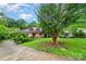 Lovely one story brick home with a large tree in the front yard, complemented by green grass and blue skies at 9139 Robert Frost Ln, Charlotte, NC 28213