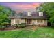 Charming one story brick home featuring three dormer windows and a landscaped front yard under a beautiful sunset sky at 9139 Robert Frost Ln, Charlotte, NC 28213