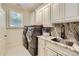 Functional laundry room with modern washer and dryer, custom cabinets, and marble countertop at 1056 James Madison Dr, Matthews, NC 28104