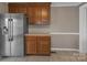 Kitchen area featuring stainless steel refrigerator, wooden cabinets, and tile flooring at 111 E Church St, Stanley, NC 28164