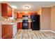 Modern kitchen with wood-look floors, cherry cabinets, and sleek black appliances at 1170 Scenic Dr, Shelby, NC 28150