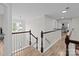 Upstairs hallway showcasing wood floors, white banisters and natural light, leading to bedrooms for a bright, open feel at 1572 Edenton Nw St, Concord, NC 28027