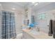 Bright bathroom featuring a shower-tub combo with blue shower curtain and light stone countertop at 18718 Peninsula Cove Ln, Cornelius, NC 28031