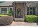 Close-up of the home's entrance featuring a stone archway and a striking wooden front door with glass details at 18718 Peninsula Cove Ln, Cornelius, NC 28031