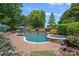 Stunning pool with lush landscaping, a stone-clad hot tub, and a built-in fireplace offers a private outdoor oasis at 18718 Peninsula Cove Ln, Cornelius, NC 28031