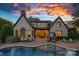 A beautiful home featuring an outdoor dining area, pool, and landscaped backyard at sunset at 18718 Peninsula Cove Ln, Cornelius, NC 28031