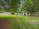 Expansive backyard featuring a well-maintained lawn, mature trees, shed, and fencing at 2223 Jon Chris Dr, Harrisburg, NC 28075