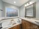 Bathroom featuring a soaking tub with an eye-catching privacy window and sink with granite countertop at 2223 Jon Chris Dr, Harrisburg, NC 28075