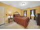 Cozy bedroom features a comfortable bed, warm yellow walls, soft carpet, and natural light at 2223 Jon Chris Dr, Harrisburg, NC 28075