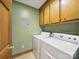 Bright laundry room features modern washer and dryer, practical overhead cabinets, and neutral tile flooring at 2223 Jon Chris Dr, Harrisburg, NC 28075